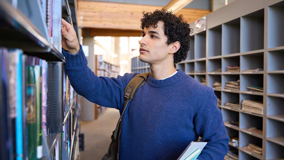 A premed student looking for MCAT study books in a library.